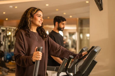 Listening to music while exercising, enduring tough workouts to maintain fitness, having a good time during exercise, a healthy lifestyle, using modern technological devices, the concept of burning fat and losing weight, a Saudi Arabian couple wearing sportswear.