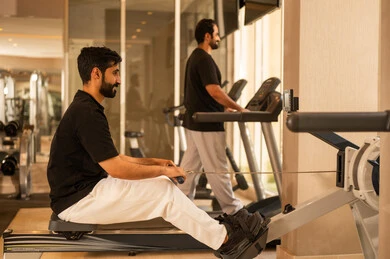 Having a good time while exercising, practicing favorite sports with friends, the importance of sports in building a strong body, paying attention to health and physical fitness, a Saudi man practicing exercises to improve body posture and balance, a young Arab Gulf Saudi man wearing sportswear exercising on a treadmill.