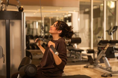 Enduring tough workouts to maintain fitness, having fun during exercise, a healthy lifestyle, using modern technological devices, the concept of burning fat and losing weight, a picture of a Gulf Arab Saudi girl wearing sportswear, listening to music while exercising.