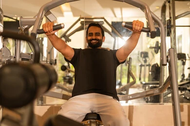 A healthy lifestyle, bodybuilding, gestures of strength and confidence, attention to health and physical fitness, use of sports equipment, a young Arab Gulf Saudi man wearing sportswear practicing weightlifting exercises, a Saudi man engaging in activities to strengthen muscles.