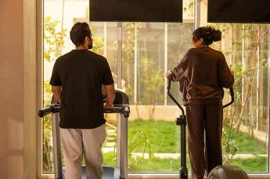 تقوية العضلات ونحت الجسم، ، تحمل التمارين القاسية للمحافظة على اللياقة, وقت ممتع أثناء التمرين ،  أسلوب حياة صحية، استخدام الأجهزة التقنية الحديثة، مفهوم حرق الدهون و إنقاص الوزن، صورة من الخلف لزوجان عربيان خليجيان سعوديان يرتديان الملابس الرياضية