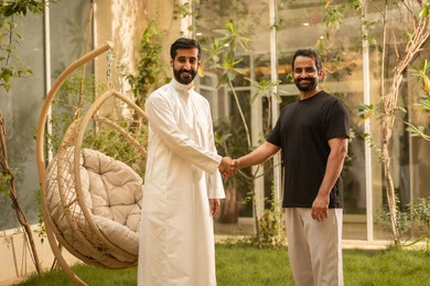 Greeting and peace, acquaintance and building social relationships, gestures of happiness and joy, a young Arab Gulf Saudi man wearing casual attire shakes hands with his friend in the park, spending enjoyable time outdoors in one of the tourist chalets in the Kingdom of Saudi Arabia.