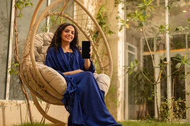 عرض شاشة سوداء فارغة عبر الجوال، استخدام جهاز تقني حديث ومتطور، شابة عربية خليجية سعودية ترتدي عباءة تجلس على الارجوحة تمسك بيدها هاتف محمول، قضاء وقت ممتع في الهواء الطلق في احدى الشاليهات السياحية، التواصل مع الاهل والاصدقاء