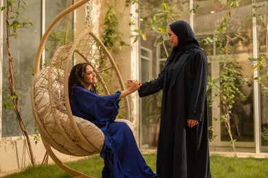 Gestures of handshake and greeting, a fun and social gathering, a young Arab Gulf Saudi woman wearing an abaya enjoying quality time with her friend in the park, having a good time outdoors in one of the tourist chalets.