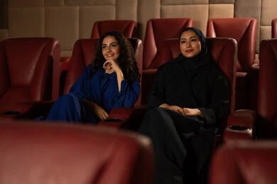 التسلية والترفيه بقضاء أوقات ممتعة،الاستمتاع بمشاهدة الأفلام داخل السينما،متابعة الفيلم المفضل، ،تعابير الاندماج والتفاعل ،  امرأة عربية خليجية سعودية محجبة ترتدي عباءه مع صديقتها ،