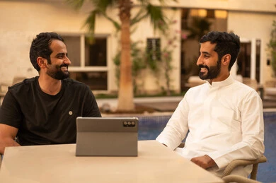 Making a video call, watching movies and series on a mobile tablet, gestures of happiness and enjoyment, outdoor youth activities, having a fun and entertaining time with friends, two Arab Gulf friends from Saudi Arabia sitting in one of the chalets.