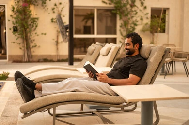 التسلية والترفيه وقضاء الوقت الممتع بالقراءة  في إحدى الشاليهات, مفهوم النظافة والاهتمام بحديقة المنزل, رجل عربي خليجي سعودي يرتدي الثوب الكاجوال , أماكن سياحية ترفيهية