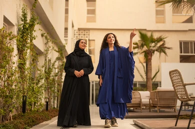 قضاء وقت ممتع مع الأصدقاء،الاستمتاع  بالاحاديث و الدردشة  ، امرأتين عربيتين خليجيتين سعوديتين تقفان في الحديقة  ، تطوير العلاقات الإجتماعية، تعابير السعادة والسرور بلمة الرفاق