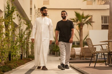 قضاء وقت ممتع ومسلي برفقة الاصدقاء، صديقان عربيان خليجيان سعوديان يقومان بالتجول والمشي في الحديقة، ايماءات السعادة والمتعة، أنشطة شبابية في الهواء الطلق