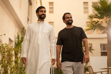 قضاء وقت ممتع ومسلي برفقة الاصدقاء، صديقان عربيان خليجيان سعوديان يقومان بالتجول والمشي في الحديقة، ايماءات السعادة والمتعة، أنشطة شبابية في الهواء الطلق