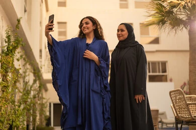 قضاء وقت ممتع مع الأصدقاء، امرأتين عربيتين خليجيتين سعوديتين تقفان في الحديقة  ، التقاط صور سيلفي تذكارية ، تطوير العلاقات الإجتماعية، تعابير السعادة والسرور بلمة الرفاق