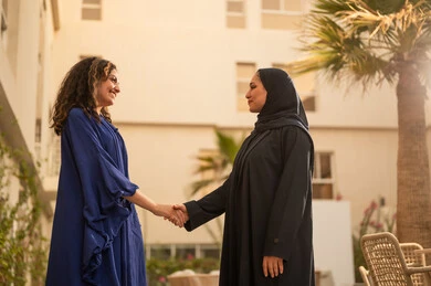 الترحيب والاستقبال بحب وحرارة, السلام والمصافحة باليد, إمرأتين عربيتين سعوديتين خليجيتين تقومان بالتصافح  بايماءات السرور والفرح في الهواء الطلق, الجسم بالطول الكامل