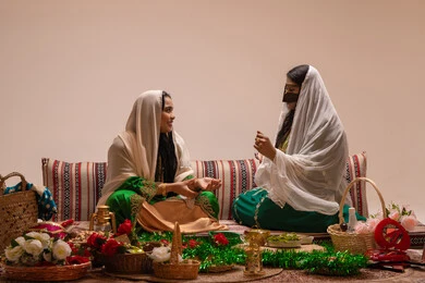 تقديم هدايا الزفاف، تعابير السعادة و السرور ، امراه عربيه خليجيه اماراتية ترتدي عباءة مطرزة تجلس مع العروس و يقومون بالمناقشة فى شي ما ، عادات الزواج والاحتفال الشعبي