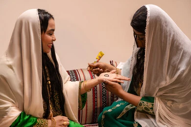 عادات المجتمع الاماراتي في الأعراس والمناسبات، التجمل بالمظهر الشعبي الأصيل، زخارف وفنون يدويه من مواد طبيعيه، إمرأة عربية خليجية إماراتية تقوم برسم و نقش الحنة على يد العروس ، مهن وأزياء تقليدية شعبية نسائية