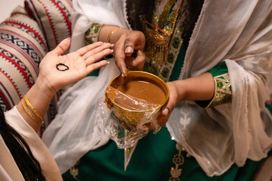 Inherited traditions in weddings and occasions, beautifying with the authentic popular appearance, decorations and handicrafts made from natural materials, a close-up image of the hand of an Emirati Gulf Arab woman drawing and engraving henna on the bride's hand, traditional women's professions and attire.