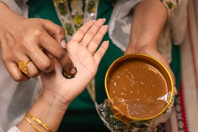 المشغولات اليدوية المزينة بنقوش فنية تقليدية، مهن وأزياء تقليدية شعبية نسائية، مظاهر الفرح والسرور في الأعراس، تقاليد الزواج والاحتفال الخليجي، الاستعداد للمناسبات السعيدة، تصوير مقرب ليد إمرأة عربية خليجية إماراتية تقوم برسم و نقش الحنة على يد العروس