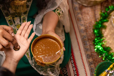 فن النقش والرسم على الأدوات الطبيعية، مهن وأزياء تقليدية شعبية نسائية، مظاهر الفرح والسرور في الأعراس، تقاليد الزواج والاحتفال الخليجي، الاستعداد للمناسبات السعيدة، تصوير مقرب ليد إمرأة عربية خليجية إماراتية تقوم برسم و نقش الحنة على يد العروس