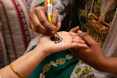 مظاهر الفرح والسرور في الأعراس، تقاليد الزواج والاحتفال الخليجي، الاستعداد للمناسبات السعيدة، زخارف وفنون يدويه من مواد طبيعيه، تصوير مقرب ليد إمرأة عربية خليجية إماراتية تقوم برسم و نقش الحنة على يد العروس ، مهن وأزياء تقليدية شعبية نسائية