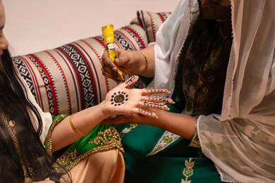 الاعتناء بالمظهر بأسلوب تقليدي، زخارف وفنون يدويه من مواد طبيعيه، عادات وتقاليد في المناسبات والأفراح السعيدة، تصوير مقرب ليد إمرأة عربية خليجية إماراتية تقوم برسم و نقش الحنة على يد العروس ، مهن وأزياء تقليدية شعبية نسائية