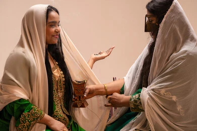 استخدام الروائح العربية الأصيلة، أصالة العادات والتقاليد الخليجية، الاحتفال بالمناسبات والأفراح السعيدة, امراة عربية خليجية اماراتية ترتدي الزي الشعبي تحمل بيدها حامل البخور( المبخرة ) تقوم بتبخير العروس، مراسم الأعراس والزواج