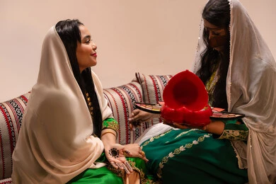 ارتداء الازياء التقليدية، مفهوم التزين والاطلالة المتألقة، العناية بالجمال و الانوثة، ايماءات السعادة والفرح، الاحتفال بليلة العمر، منتجات ومساحيق التجميل, مناسبات وأفراح واحتفالات سعيدة، سيدة عربية خليجية اماراتية تقوم بوضع المكياج للعروسة