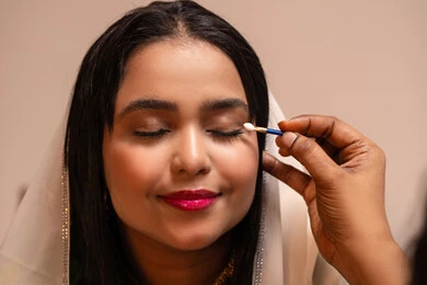 Taking care of beauty and femininity, gestures of happiness and joy, the concept of adornment and a radiant appearance, celebrating the night of a lifetime, beauty products and cosmetics, happy occasions and celebrations, a close-up image of an Emirati Gulf Arab woman applying makeup to the bride, wearing traditional attire.