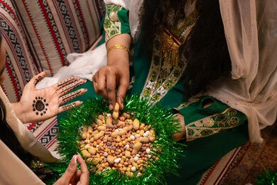 ارتداء الازياء الشعبية في المناسبات والاحتفالات، منتج محلي وطني ، تراثيات وشعبيات اماراتيه تقليديه ،صورة مقربة لامرأتان عربيتان خليجيتان اماراتيتان ترتديان الزي التقليدي تقومان بتناول المكسرات المشكلة، سناك صحي وخفيف