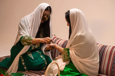 التجمل والاهتمام بالمظهر الخارجي على الطريقة الشعبية، زخارف وفنون يدويه من مواد طبيعيه، عادات وتقاليد في المناسبات والأفراح السعيدة، إمرأة عربية خليجية إماراتية ترتدي الزي التراثي و تقوم برسم و نقش الحنة على يد العروسة، مهن وأزياء تقليدية شعبية نسائية