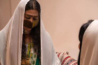 Wearing traditional Emirati folk attire, spending enjoyable time with family and relatives, a close-up image of an Arab Gulf Emirati woman wearing a burqa and a white hijab sitting with her friend in the council.