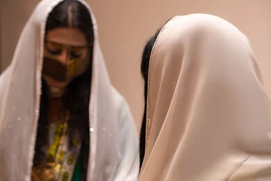 Spending quality time with family and relatives, a close-up image of an Arab Gulf Emirati woman wearing a burqa and a white hijab sitting with her friend in the council, wearing traditional Emirati folk attire.
