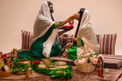 مفهوم التزين والاطلالة المتألقة، العناية والاهتمام بالأناقة والجمال، مناسبات وأفراح واحتفالات سعيدة، منتجات ومساحيق التجميل، سيدة عربية خليجية اماراتية تقوم بوضع المكياج للعروسة، إيماءات السعادة والفرح ، الاحتفال بليلة العمر