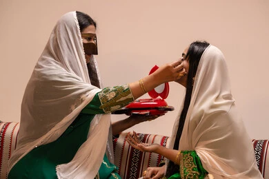 منتجات ومساحيق التجميل, مناسبات وأفراح واحتفالات سعيدة، العناية والاهتمام بالأناقة والجمال، مفهوم التزين والاطلالة المتألقة، سيدة عربية خليجية اماراتية تقوم بوضع المكياج للعروسة، إيماءات السعادة والفرح ، الاحتفال بليلة العمر