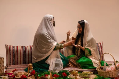 The authenticity of Gulf customs and traditions, wedding ceremonies, celebrating occasions and happy events, an Emirati Arab woman wearing traditional attire holding a incense burner (mabkharah) in her hand, performing incense for the bride, and applying perfume with musk and oud.