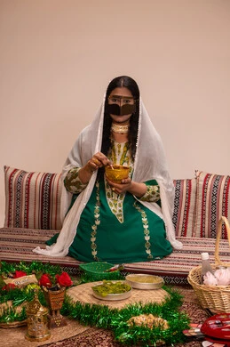 مهنة تقليدية شعبية نسائية، التجمل والتزيين في يوم الزفاف، فنون ونقوش وزخارف يدويه من مواد طبيعيه، عادات وتقاليد في المناسبات والأفراح السعيدة، إمرأة عربية خليجية إماراتية ترتدي البرقع وحجاب ابيض تقوم بتحضير خلطة الحناء