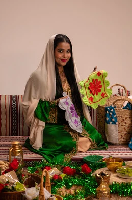Traditional Emirati heritage and folk culture, wearing traditional attire during occasions and celebrations, a local national product, an Arab Gulf Emirati woman wearing an embroidered abaya holding a piece of fabric made with traditional hand embroidery, looking at the camera with gestures of happiness and joy.