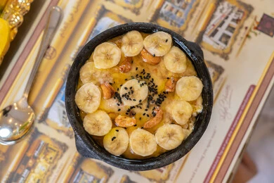 أصالة المذاق الخليجي وكرم الضيافة الشرقية،صورة مقربة لطبق حلوى عربي تقليدي مزين بشرائح الموز والمكسرات المحمصة، تقديم الحلويات التراثية بأسلوب عصري جذاب أصالة المذاق الخليجي وكرم الضيافة الشرقية،صورة مقربة لطبق حلوى عربي تقليدي مزين بشرائح الموز والمكسرات المحمصة، تقديم الحلويات التراثية بأسلوب عصري جذاب