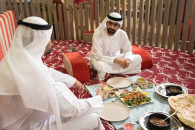 مشاركة الطعام بروح الود والتقارب، رجلان عربيان خليجيان إماراتيان يرتديان الكندورة والغترة يجلسان معًا داخل خيمه في أجواء دافئة ويتناولان وجبة تقليدية لذيذة من الأرز والمأكولات الشرقية، مفهوم الضيافة العربية والأجواء الاجتماعية، خلفية داخلية مليئة بالتفاصيل الشرقية الجميلة. مشاركة الطعام بروح الود والتقارب، رجلان عربيان خليجيان إماراتيان يرتديان الكندورة والغترة يجلسان معًا داخل خيمه في أجواء دافئة ويتناولان وجبة تقليدية لذيذة من الأرز والمأكولات الشرقية، مفهوم الضيافة العربية والأجواء الاجتماعية، خلفية داخلية مليئة بالتفاصيل الشرقية الجميلة.