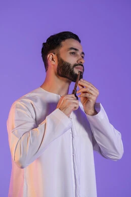 تعابير الاعجاب بالنفس، قص و تصفيف الذقن والشارب, مركز تجميلي رجالي، مفهوم العناية و الاهتمام بالجمال والمظهر الخارجي، بورتريه لرجل عربي خليجي اماراتي يرتدي الكندورة الاماراتية و يمسك المقص, خلفية بنفسجية