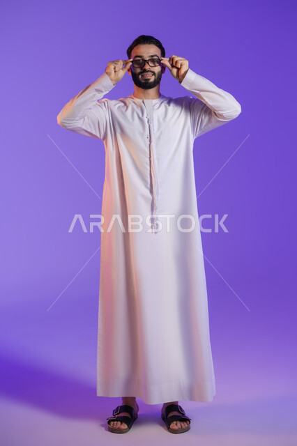 محاولة تعديل البصر، الاهتمام بالمظهر الخارجي، ارتداء النظارات الخاصة بضعف النظر، بورتريه لرجل عربي خليجي اماراتي يرتدي الكندورة الاماراتية و يضع على وجهه نظارة طبية, خلفية بنفسجية