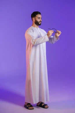 تحسين الرؤية وحماية العينين, مفهوم محاولة تعديل البصر، الاهتمام بالمظهر الخارجي، ارتداء النظارات الخاصة بضعف النظر، بورتريه مقرب لرجل عربي خليجي اماراتي يرتدي الكندورة الاماراتية و ينظر للنظارة الطبية, خلفية بنفسجية