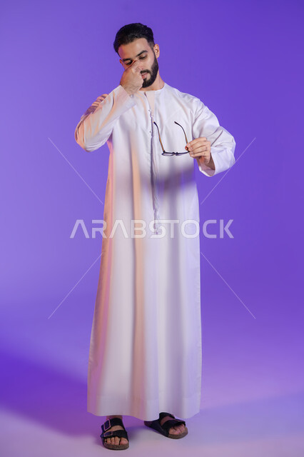 إيماءات التعب والإرهاق، آلام الشقيقة والصداع النصفي, الإحساس بوجع الرأس و الدوخة, الحاجة للعلاج والراحة, بورتريه لرجل عربي خليجي اماراتي يرتدي الكندورة الاماراتية و يمسك النظارة الطبية, خلفية بنفسجية