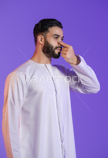 Gentle nose cleaning, easy blackhead removal, effective cosmetic products and modern techniques, Arab man's awareness of the importance of personal care, close-up portrait of an Emirati Gulf Arab man wearing an Emirati kandura and applying a mask to his nose, purple background