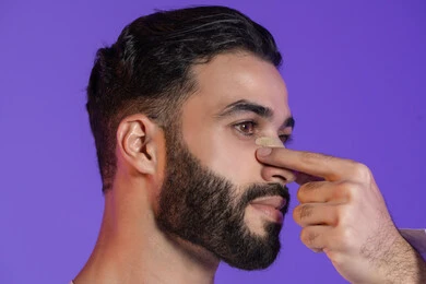 العناية بالبشرة الدهنية, إزالة الرؤوس السوداء بسهولة, منتجات تجميلية فعالة وتقنيات حديثة، وعي الرجل العربي بأهمية العناية الشخصية، بورتريه مقرب لرجل عربي خليجي اماراتي يرتدي الكندورة الاماراتية و يقوم بوضع ماسك على أنفه, خلفية بنفسجية