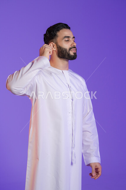 استخدام أدوات العناية بالأذن, الاهتمام بالصحة والنظافة, روتين نظافة الأذنين اليومية، بورتريه لرجل عربي خليجي اماراتي يرتدي الكندورة الاماراتية و يمسك بيده نكاشة قطنية, خلفية بنفسجية