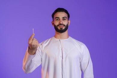 Attention to detail in personal hygiene, use of cotton swabs and buds, daily ear hygiene routine, portrait of an Emirati Gulf Arab man wearing the Emirati kandura and holding a cotton bud in his hand, purple background