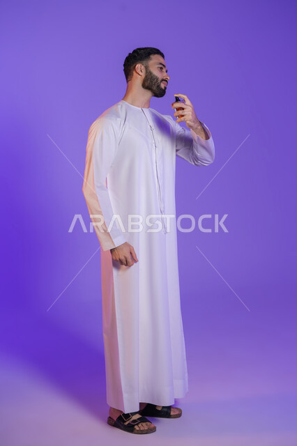Good fragrant smells, use of natural essential oils, concept of elegance and interest in outward appearance, marketing of perfume products, Arab Gulf perfumes, portrait of an Arab Gulf Emirati man wearing the Emirati kandura and holding a bottle of perfume, purple background