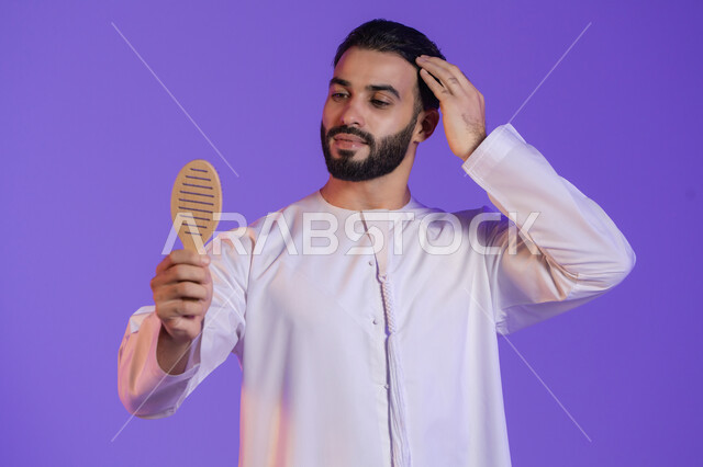 المحافظة على الأناقة, تحسين المظهر الخارجي, شعر صحي وأنيق، مفهوم الاهتمام بالجمال، بورتريه لرجل عربي خليجي اماراتي يرتدي الكندورة الاماراتية و يقوم بتصفيف شعره باستخدام الفرشاة, خلفية بنفسجية