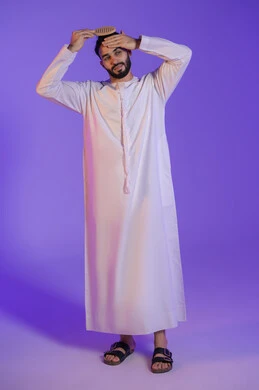 ترتيب وتمشيط الشعر، مفهوم العناية والاهتمام بالجمال والأناقة والمظهر الخارجي، بورتريه لرجل عربي خليجي اماراتي يرتدي الكندورة الاماراتية و يقوم بتصفيف شعره باستخدام الفرشاة, خلفية بنفسجية