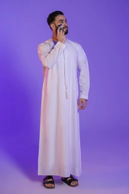 القيام بإزالة شعر الوجه باستخدام شفرة الحلاقة الرجالية، مفهوم العناية بالبشرة والاهتمام بالمظهر الخارجي، المحافظة على الأناقة والنظافة الشخصية، بورتريه لرجل عربي خليجي اماراتي يرتدي الكندورة الاماراتية و ينظر بعيدا, خلفية بنفسجية