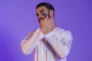 Personal care routine, removing facial hair with a men's razor, the concept of skin care and attention to one's appearance, maintaining elegance and cleanliness, a portrait of an Emirati Gulf Arab man wearing an Emirati kandura, purple background